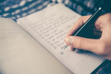 Main qui coche une liste de tâches dans un carnet à petits carreaux