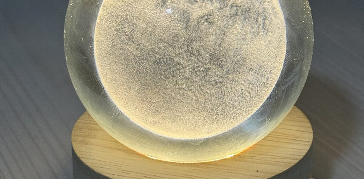 Veilleuse en forme de lune allumée sur un socle en bois
