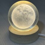 Veilleuse en forme de lune allumée sur un socle en bois