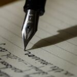 Une main écrit au stylo-plume dans un carnet ouvert