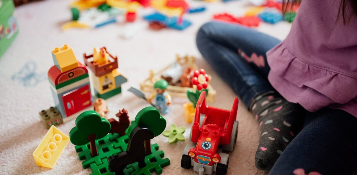 Enfant assis par terre au milieu de jouets de construction colorés