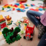 Enfant assis par terre au milieu de jouets de construction colorés