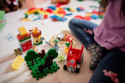 Enfant assis par terre au milieu de jouets de construction colorés