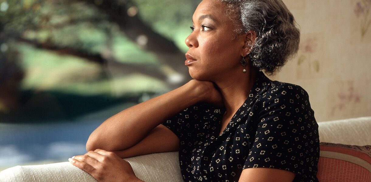Femme pensive regardant par la fenêtre, perdue dans ses pensées