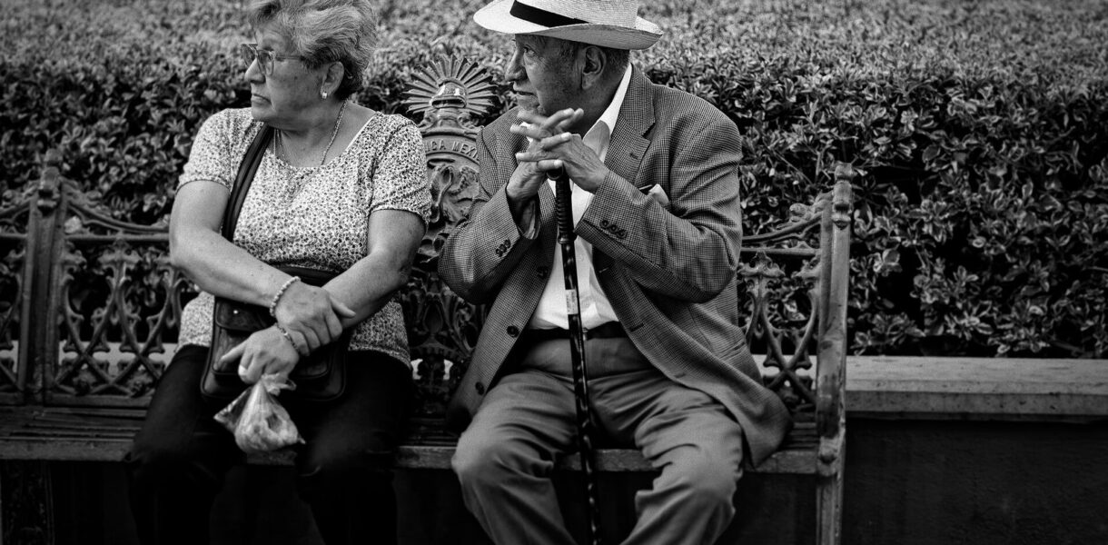 Deux personnes âgées en conversation sur un banc, photo en noir et blanc