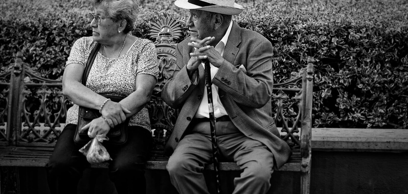 Deux personnes âgées en conversation sur un banc, photo en noir et blanc