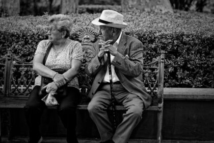 Deux personnes âgées en conversation sur un banc, photo en noir et blanc